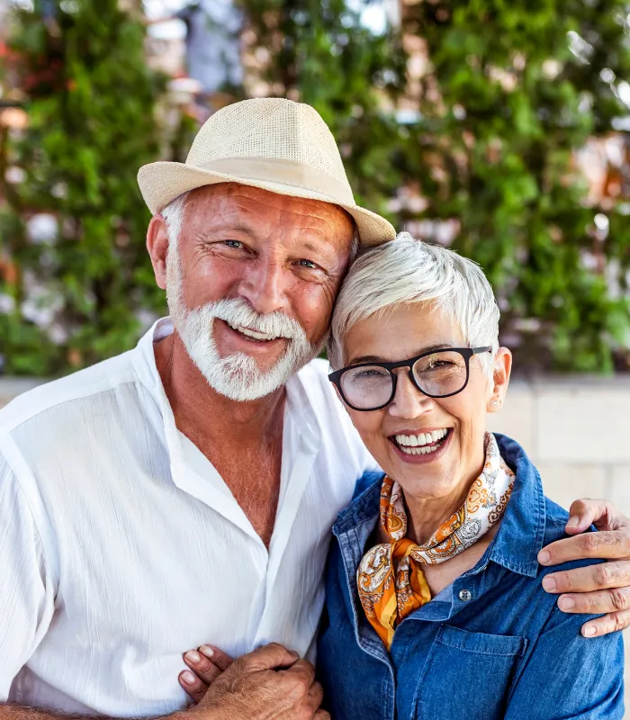 Elderly Couple Hugging And Smiling With New Teeth Implants