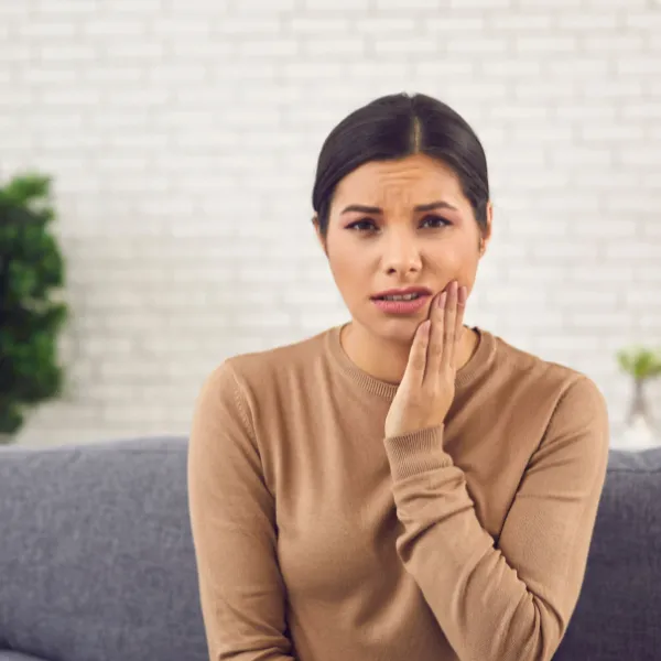 Woman Who Needs Tooth Extraction Holding Face